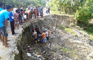 Evakuasi pengendara sepedah motor terperosok di Jalan Desa Mentoro yang dilakukan oleh warga setempat. (khoirul Huda/bhirawa)