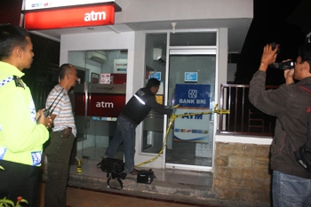 Petugas Kepoisian dari Polsek Kota saat memberikan garis polisi pada ATM BRI yang gagal di bobol kawanan pencuri (Khoirul Huda/bhirawa)