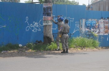 Satpol PP Kota Batu terlihat sedang mengamankan banner illegal yang pemasangannya dipaku di pohon.