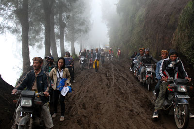 Warga Tengger di Kecamatan Tosari Kabupaten Pasuruan saat melewati jalan desanya yang terkena longsoran tanah. 