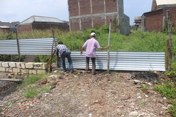 Salah satu warga yang memiliki tanah di Medokan Tambak Gang III, Kelurahan Medokan Ayu, Kecamatan Rungkut membongkar pembatas tanah kavling yang telah diklaim orang lain, Selasa (5/1) kemarin. [Gegeh Bagus/bhirawa] 