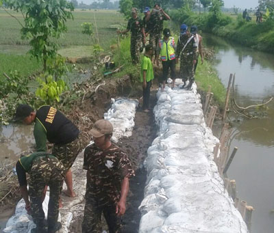 Warga bersama Banser Ansor membenahi tanggul sungai di Desa Pucang Simo yang jebol akibat banjir, Senin (4/1). Akibat jebolnya tanggul sungai ratusan hektare sawah terendam banjir.