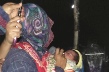 Tampak seorang ibu menggendong bayi yang ditemukan di teras rumah Kemis, Sabtu (2/1). [sudarno/bhirawa]