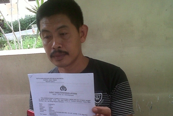 Warga Perumahan Griya Permata Alam, Suwanto, menunjukkan surat tanda telah membuat laporan pengaduan atas aksi semena oknum polisi.