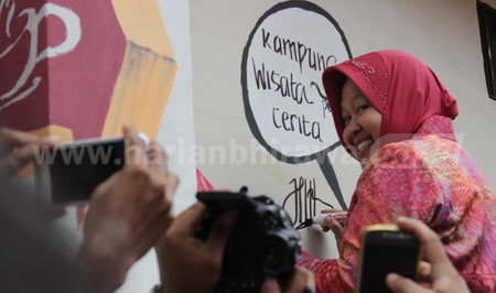 Wali Kota Surabaya Tri Rismaharini  menorehkan tulisan 'Kampung Wisata Penuh Cerita' yang diakhiri dengan tanda tangannya, Minggu (21/2). Torehan tulisan ini sekaligus untuk menandai perubahan kawasan Dolly menjadi Kampung Wisata. [gegeh]