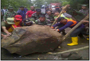 Anggota Koramil dan Polsek Pacet serta masyarakat sedang menggelundungkan batu besar itu hanya dengan batang bambu. [hasan amin/bhirawa]