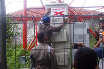 Satpol PP Kabupaten Sampang, menyegel tower nunggak retribusi tiga tahun di Desa Paseyan Sampang kota. [norkholis/bhirawa]