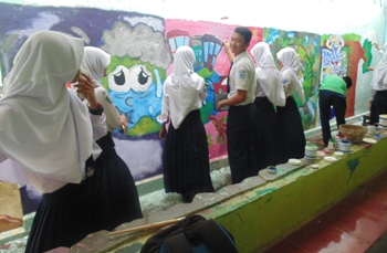 Sejumlah siswa SMPN I Panji Kabupaten Situbondo tampak tekun saat membuat mural (lukisan seni modern) digedung sekolah setempat kemarin. [sawawi/bhirawa]