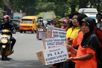 Puluhan karyawan meminta-minta ke pengguna jalan di jalan raya Gempol-Pasuruan, Senin (1/2). Aksi mereka dipicu lantaran mereka secara mendadak tidak diperbolehkan masuk tanpa alasan jelas. [hilmi husain/bhirawa]