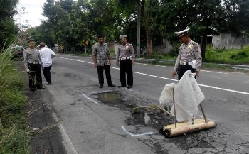 Petugas dari jajaran Satlantas Polres Jombang, saat memberikan Tanda Cat Putih dilubang Jalur Nasional Rute 15 Jombang. [ramadlan/bhirawa] 