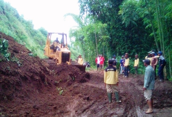Alat berat sedang mengeruk material longsoran yang menutup jalan desa Pandansari kec Poncokusumo kab Malang (supriyanto/bhirawa)