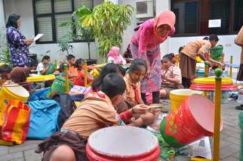 Kabid Pendidikan Dasar Dindik Surabaya Eko Prasetyoningsih ikut terlibat dengan ratusan siswa melukis tong sampah di lapangan tengah kantor Dindik Surabaya. [adit hananta utama/bhirawa]