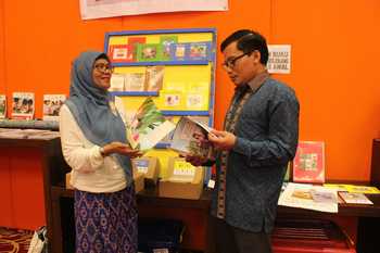 Staf Khusus Kemendikbud M Chozin Amirullah (kanan) sedang membaca buku dalam taman bacaan karya sekolah mitra USAID-PRIORITAS Jatim yang dipamerkan dalam Lokakarya Pengembangan Kabupaten/Kota Literasi di Surabaya. [achmad tauriq/bhirawa]