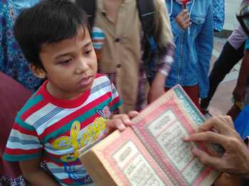 Anggota Forum Lingkar Pena (FLP) mengajak warga membaca Alquran di Alun-alun Kab Sidoarjo. [achmad suprayogi/bhirawa]