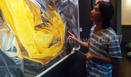 Suwandi Waeng saat mengamati salahsatu lukisanya di Lobby hotel Artotel Surabaya. [achmad tauriq]