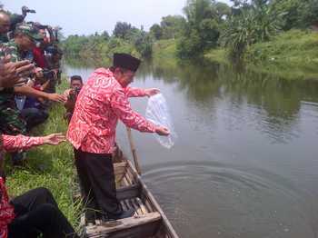 Wali kota Mas'ud Yunus menebar benih ikan rengkik di Sungai Brantas, kawasan Jalan Prapanca, Kota Mojokerto, Kamis (25/8) kemarin. (kariyadi/bhirawa).
