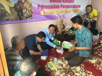 Camat Montong Agus Wijaya, Danramil dan pemilik Resto & Kafe' Baca Iing Lutfiyanan saat menandatangani salah satu buku sebagai bentuk secara simbolis perpusataan dan kafe telah dibuka. (Khoirul Huda/bhirawa)