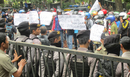 Polisi berjaga-jaga di depan pagar Kantor DPRD Tulungagung, Rabu (14/9). Mereka melakukan pagar betis di tengah pengunjuk rasa yang meminta pencopotan Kepala Dinas Pendidikan Kabupaten Tulungagung. [wiwieko]