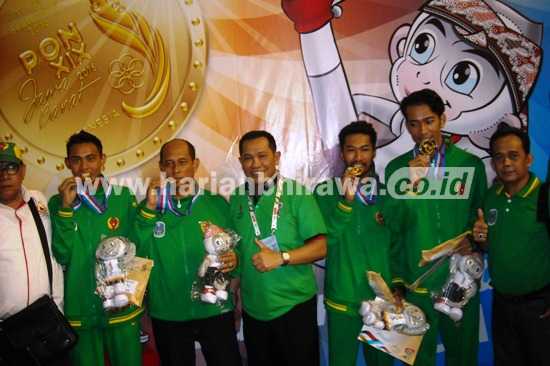 Manajer Sepak Takrawa, Hudiono (tengah) bersama atlet Syamsul-Rijal dan pelatih usai menerima pengalungan medali emas di nomor double event regu. [wawan triyanto/bhirawa]