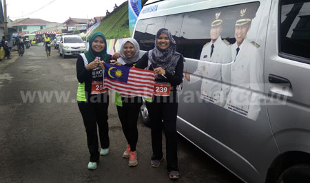 Tiga peserta dari negara Malaysia berfoto berlatar mobil bergambar Bupati Pasuruan dan Wakil Bupati Pasuruan di acara International Bromo Marathon 2016, Minggu (4/9) pagi. [hilmi husain]