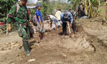 Anggota TNI bersama masyarakat bergotong royong dengan alat seadanya membangun jalan dan membuat jalan tembus di desa Solor Cermee. (Samsul Tahar/Bhirawa)