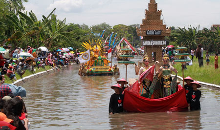 Para peserta Carnival On The River 2016 di Kabupaten Pasuruan memperagakan busana di atas rakit yang menelusuri aliran Sungai Complong Kejayan Kabupaten Pasuruan sepanjang 1 kilometer, Minggu (9/10). [hilmi husain]