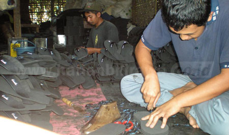 Salah satu pekerja, Mujiono saat memproses pembuatan sandal spon yang dikerjakan di area rumahnya di Desa Candirenggo Kec Singosari Kab Malang. [cahyono]