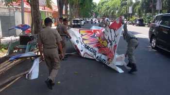 Satuan Polisi Pamong Praja saat melakukan penurunan paksa banner dan baliho yang tidak berijin. (samsul Tahar/Bhirawa)