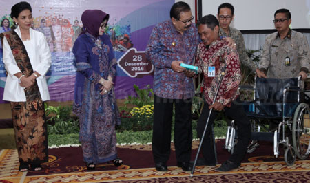 Gubernur Jatim Dr H Soekarwo didampingi istri Dra Hj Nina Soekarwo menyerahkan kursi roda secara simbolis kepada disabilitas di acara Peringatan HKSN, PHI dan HDI Tahun 2016 di Gedung Negara Grahadi, Rabu (28/12).