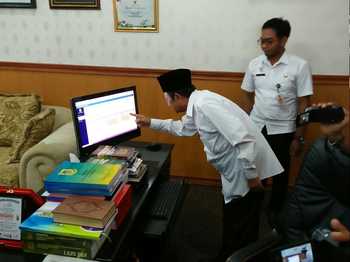 Wali Kota Mas'ud Yunus melihat monitor daya absensi PNS di ruang kerjanya saat launching absensi finggerprint. [kariyadi/bhirawa]